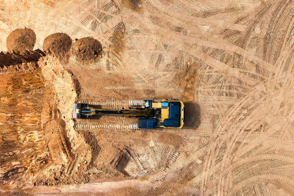 Aerial view of a small excavator digging a narrow trench