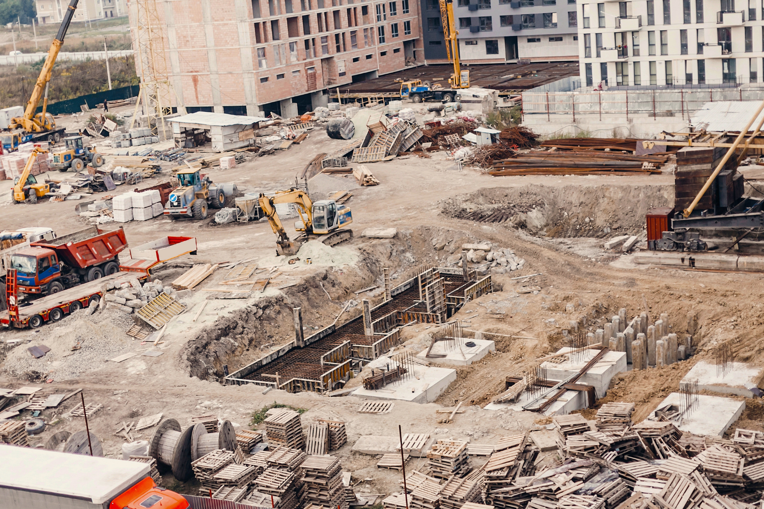 Excavator in near unfinished concrete building foundations