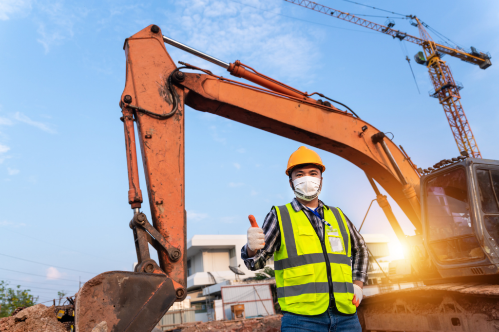 an excavator and a worker with a safety gear