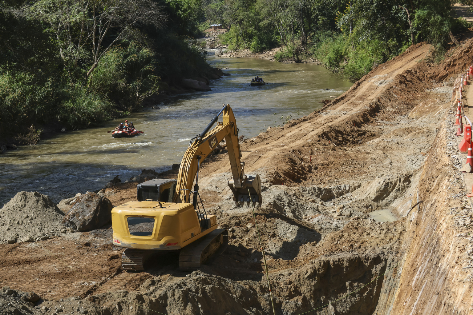 Small yellow excavator digging near a wooded area