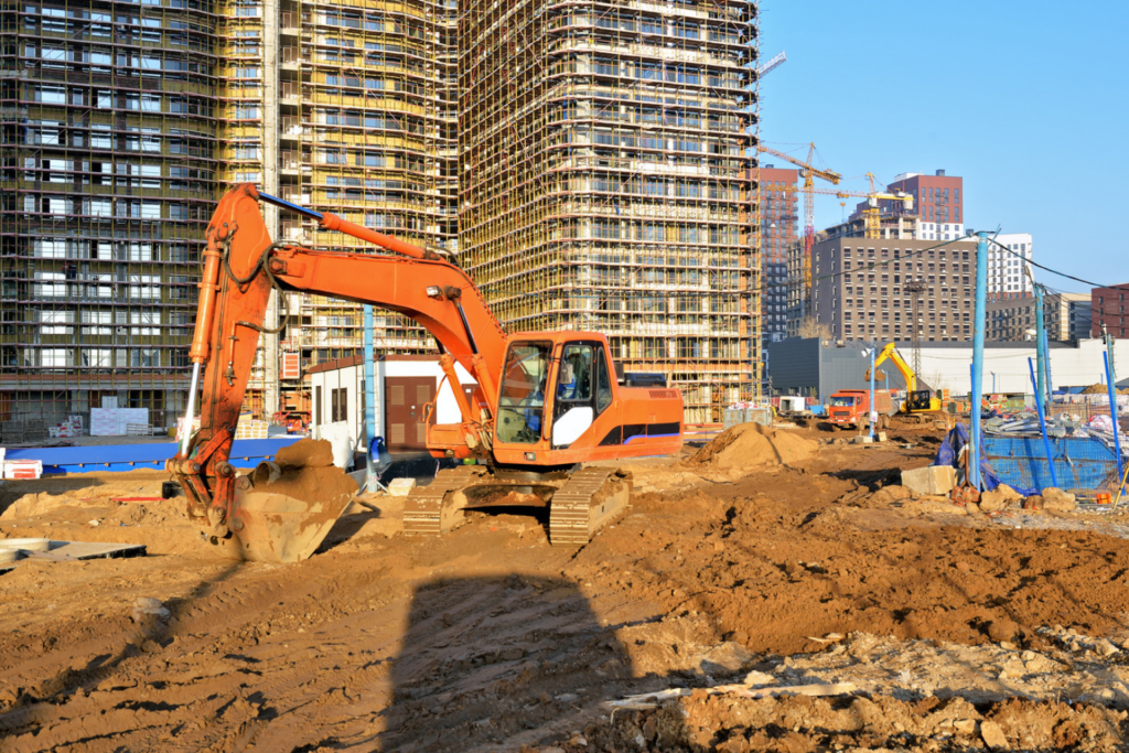 Orange excavator moving rock and dirt on a hillside.