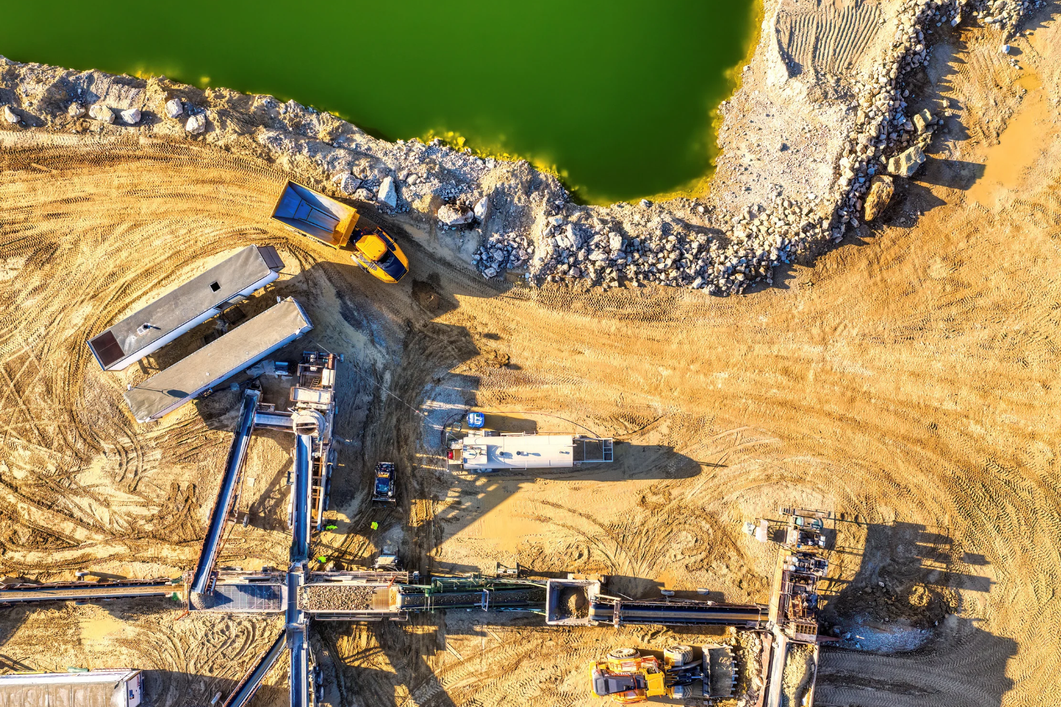 Yellow excavator moving dirt on a dusty construction site.