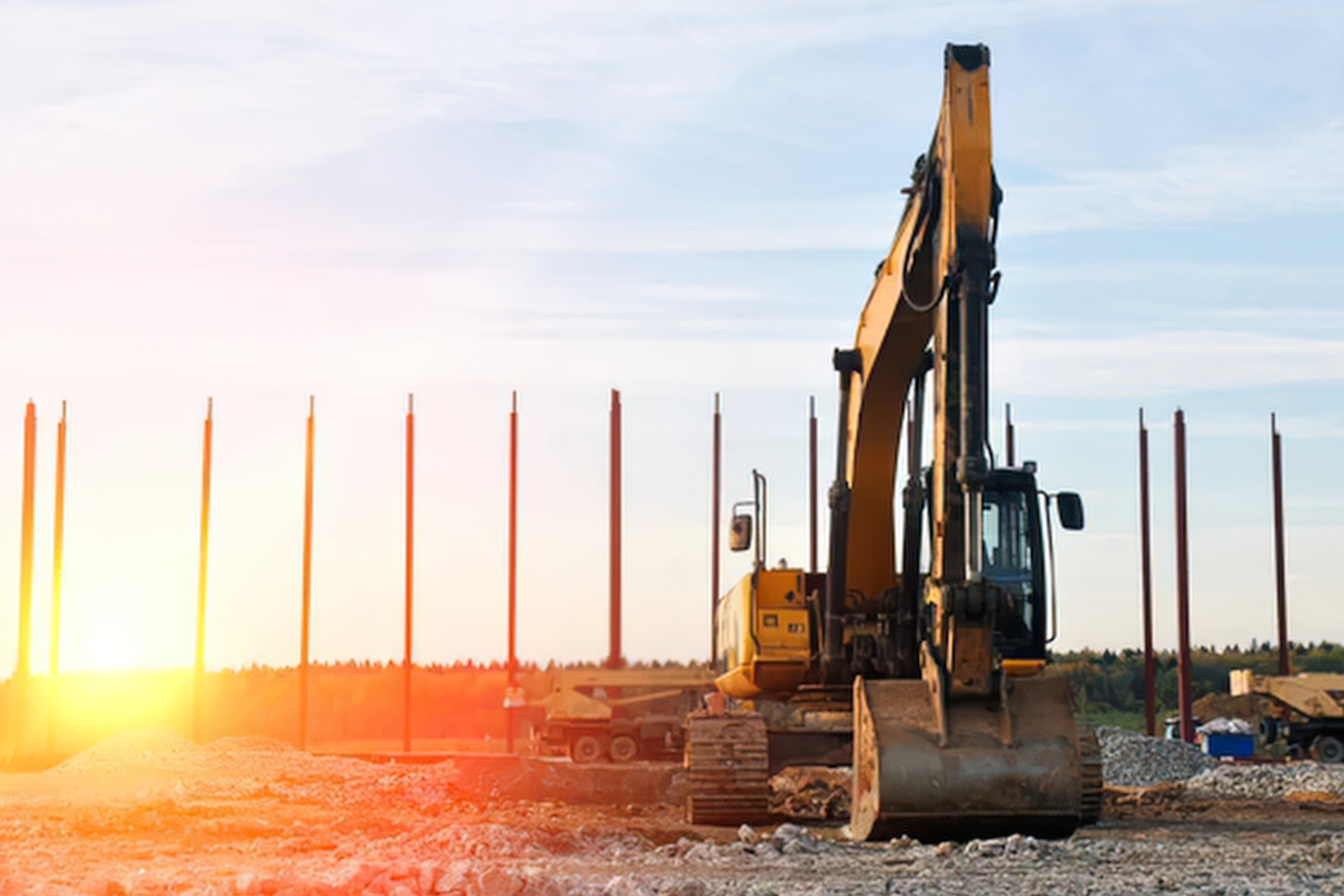 Silhouetted excavator against a bright sunset horizon