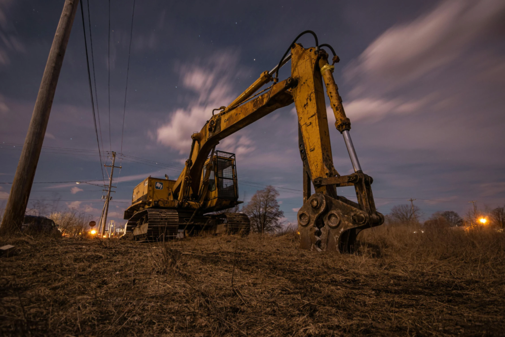 Excavator positioned on top of a large dirt mound.