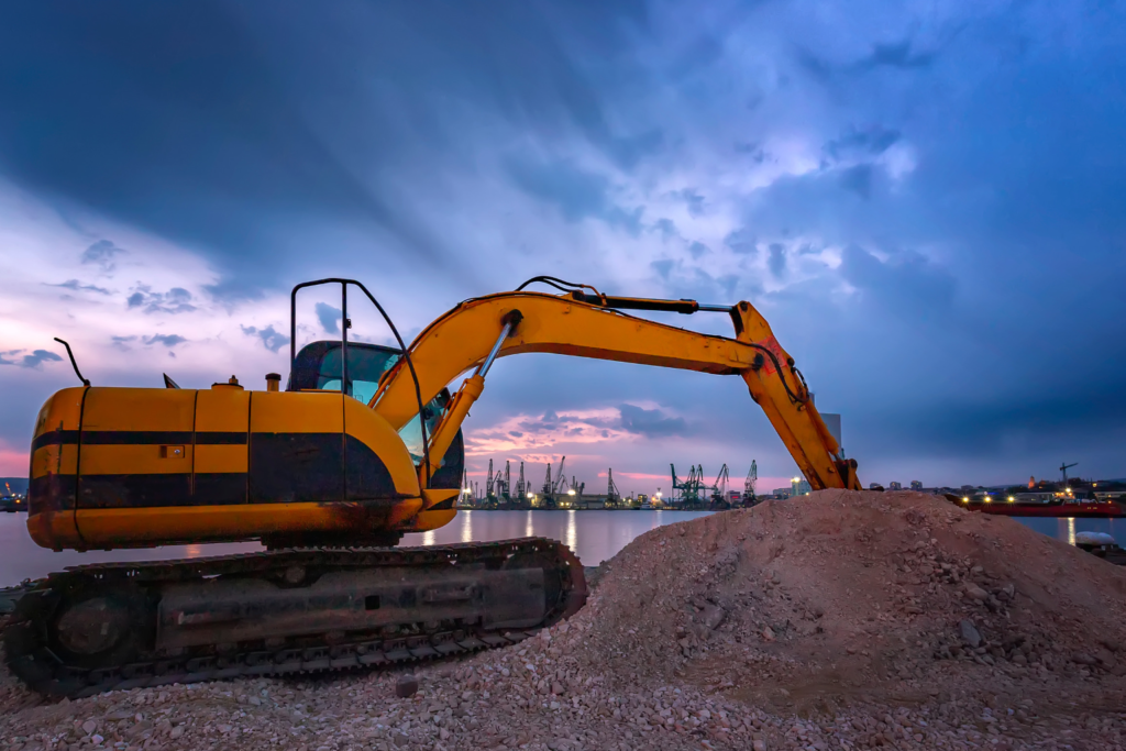 Excavator operating under a dramatic sunset sky.