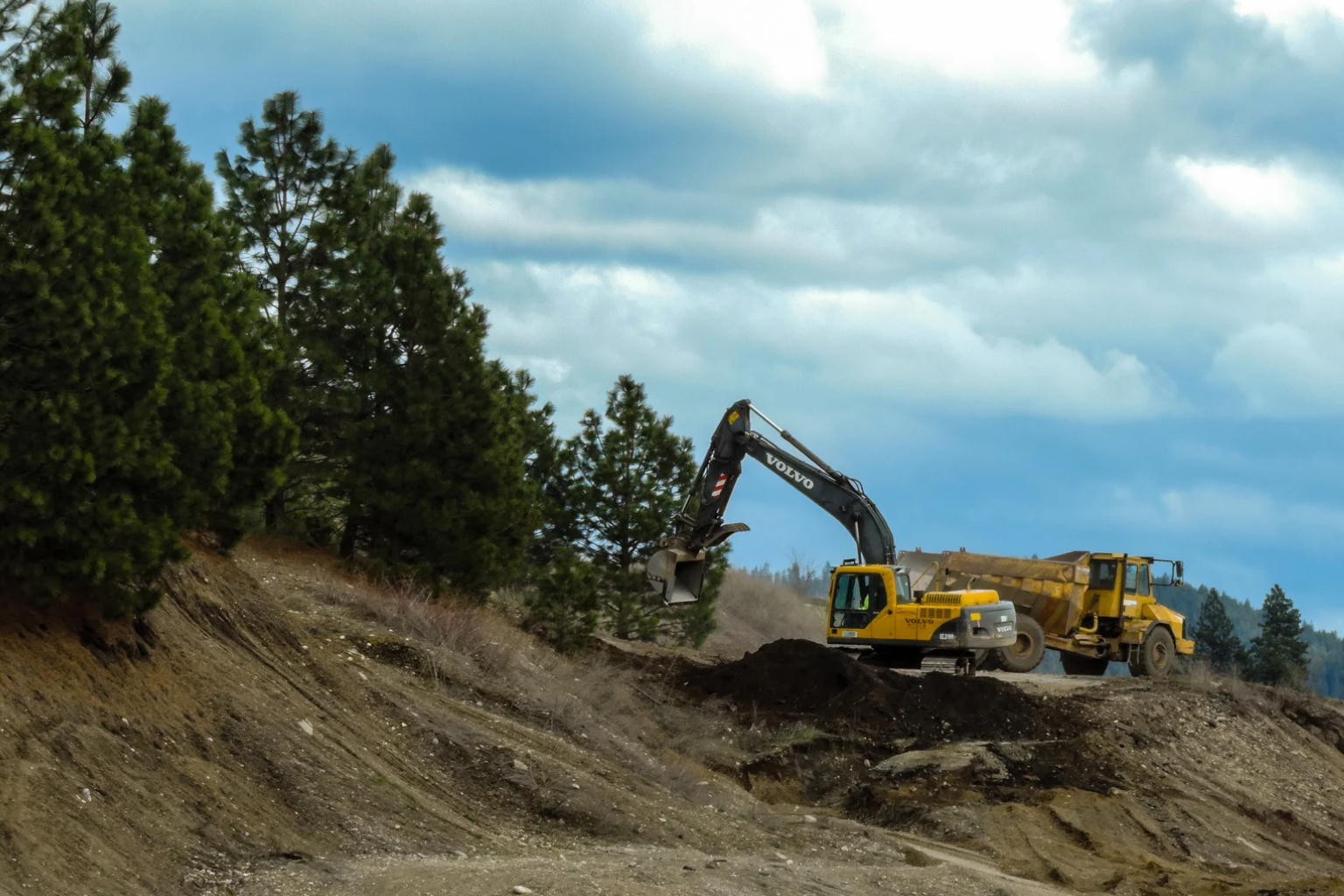 Excavator moving dirt on a bright, sunny day.