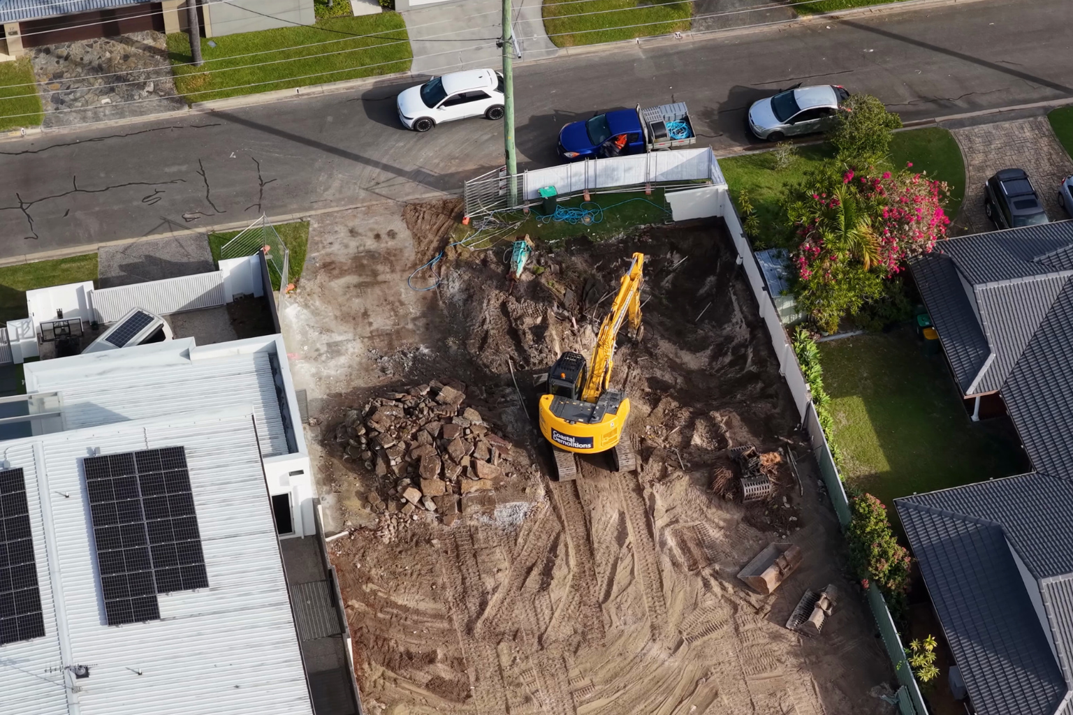 Excavator digging on a roadside construction site.