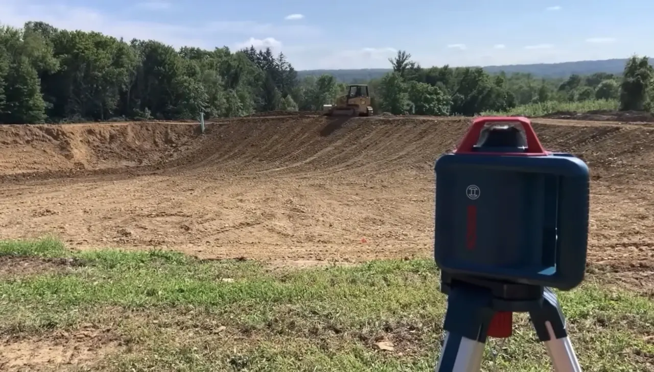 Pond earthwork with a grade-control instrument in the foreground