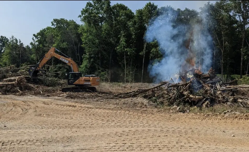 Excavator clearing and handling woody material